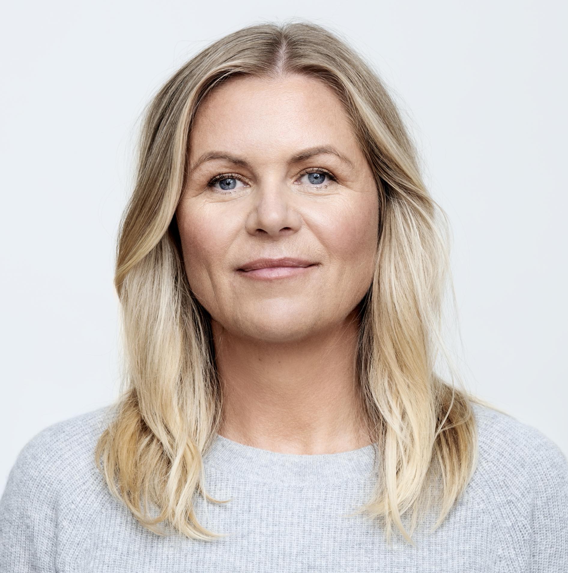 Kvinne med blondt halvlangt hår og lys grå genser