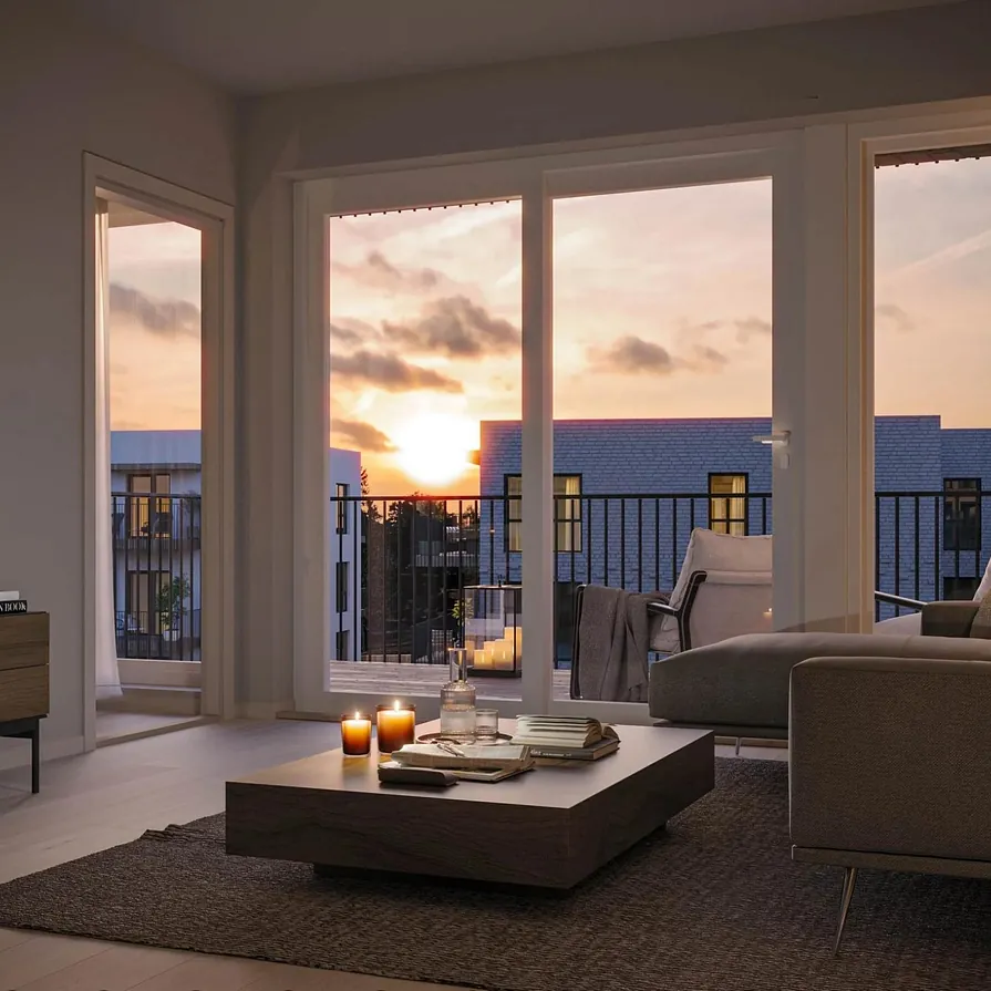 Stue i lune toner med mørk sofa, lavt bord og store vinduer med utsikt mot solnedgang og balkong.