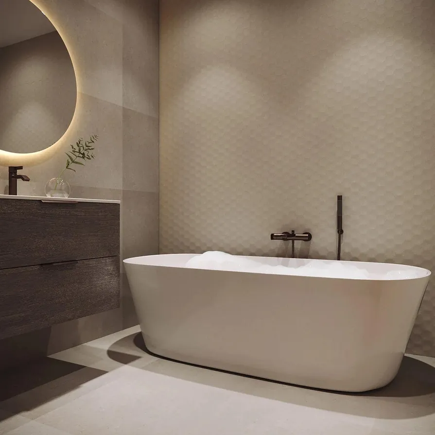 Lunt bad med frittstående badekar, store fliser og bakbelyst speil med rund form.