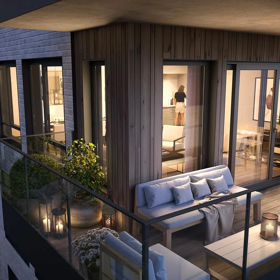 Møblert hjørnebalkong med puter og planter, og innsyn til stue og kjøkken med kveldsmys.