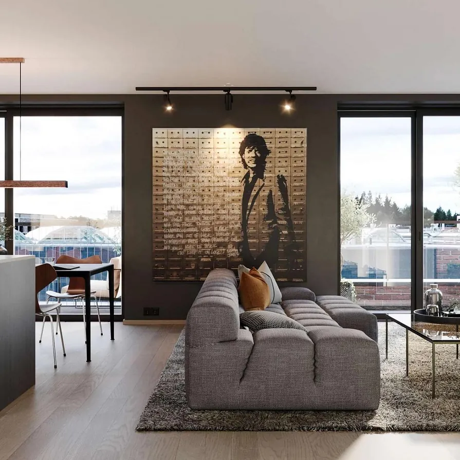 Stue med moderne kunst, grå sofa og store vindusflater som slipper inn mye dagslys.