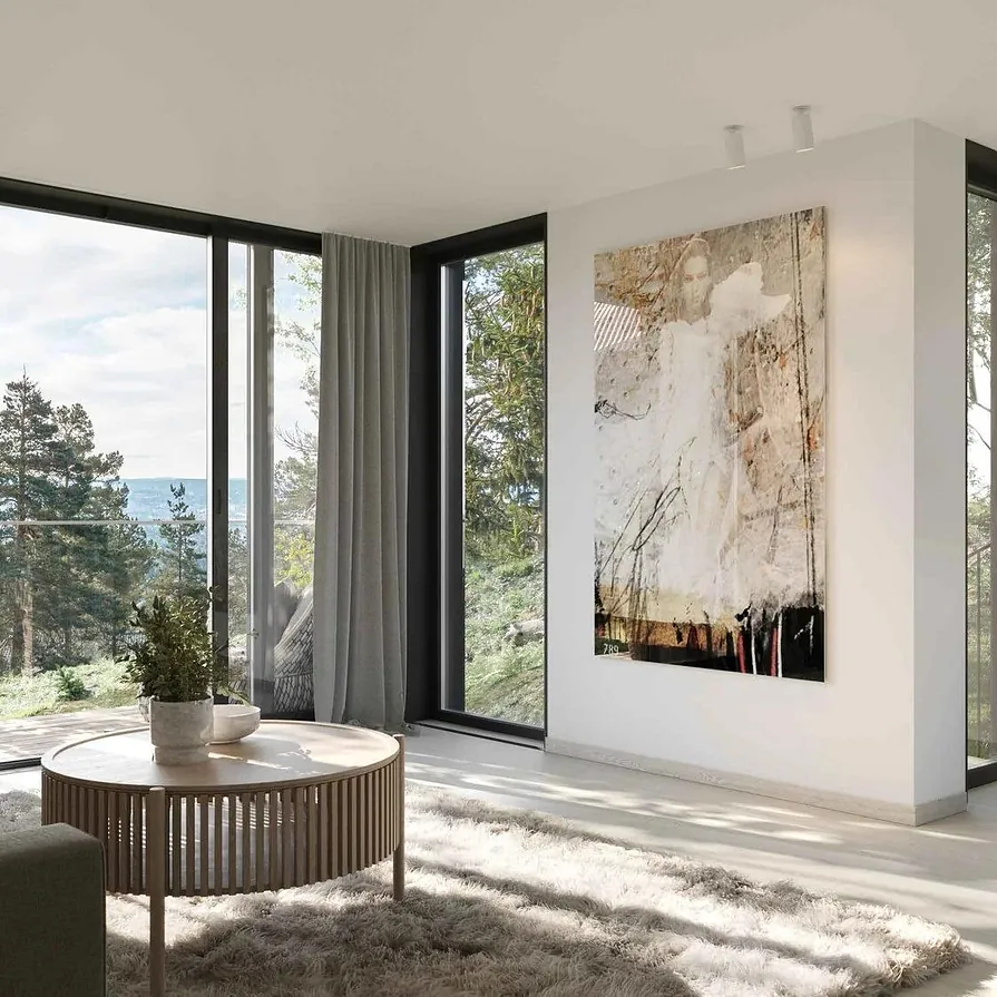 Lys stue med store vinduer, sofagruppe, rund bord og kunst på veggen med utsikt mot hage.