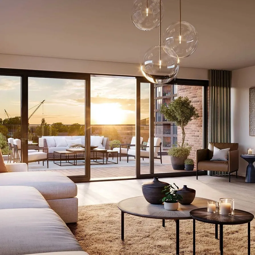 Stue med lys sofa, varme toner og utgang til romslig terrasse i solnedgang.